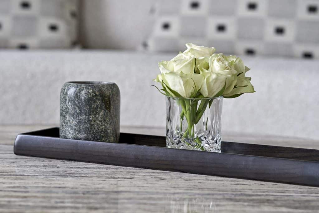 Alexander lamont accessories, dark wood tray with white roses in a glass next to a vase