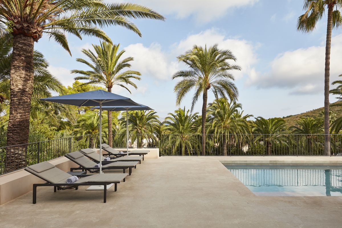 Pairs of modern sun loungers beside a pool in natural stone. 