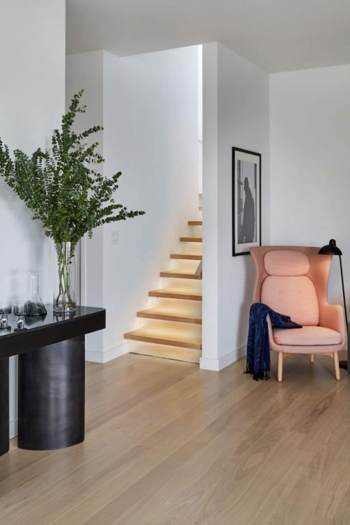 Mirrored and lit staircase in a manhattan penthouse with Ro Armchair by Fritz Hansen.