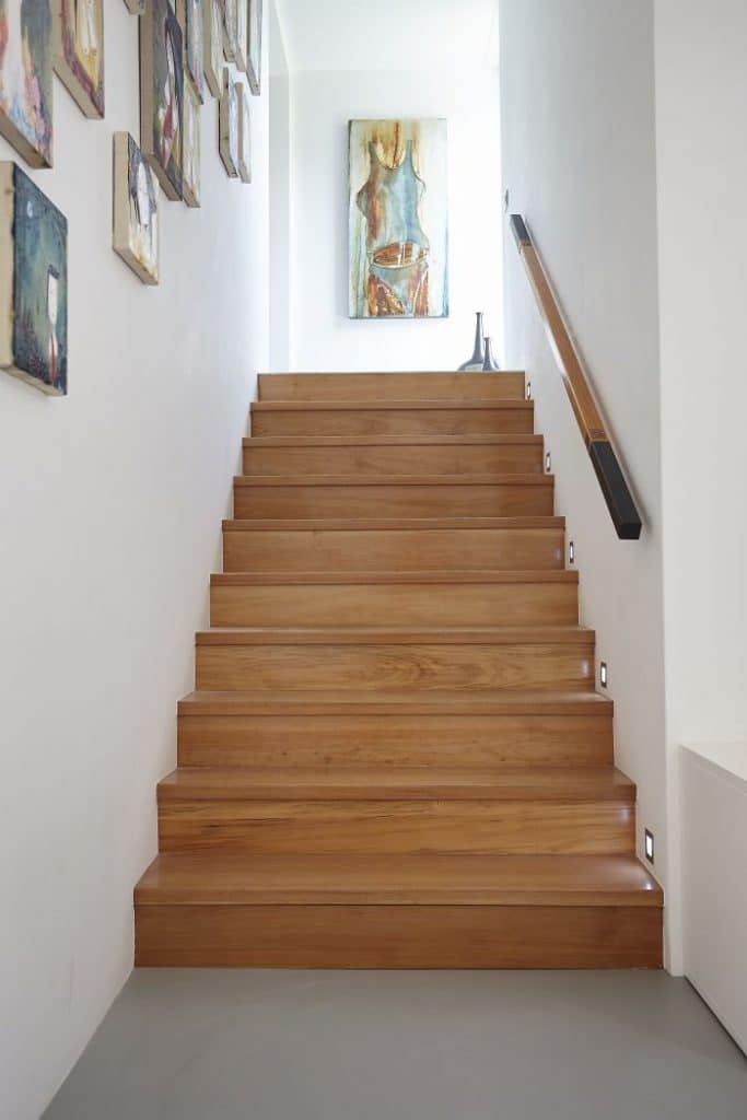 A wooden staircase and gallery wall of oil paintings.