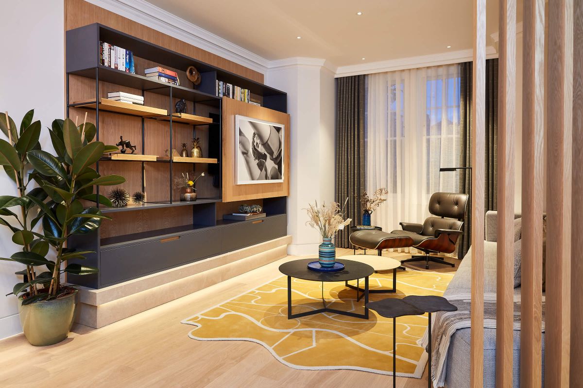 Mustard yellow rug in mid century inspired living room with Eames Lounger and TV unit with stone plinth.