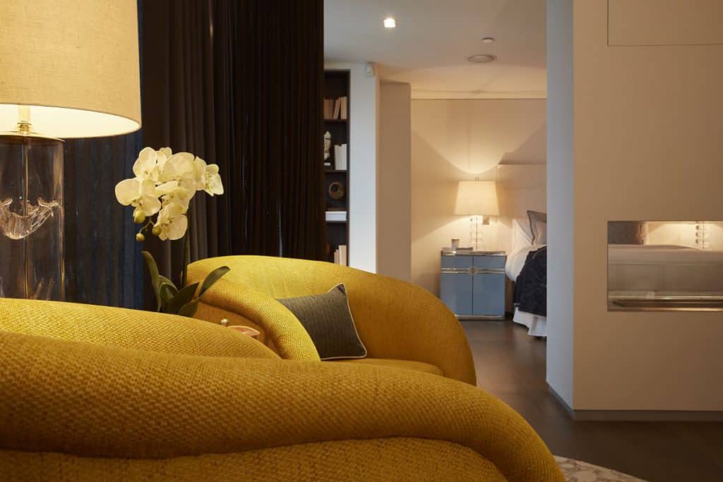 A pair of collectors armchairs create a soft seating area in this principle bedroom suite.