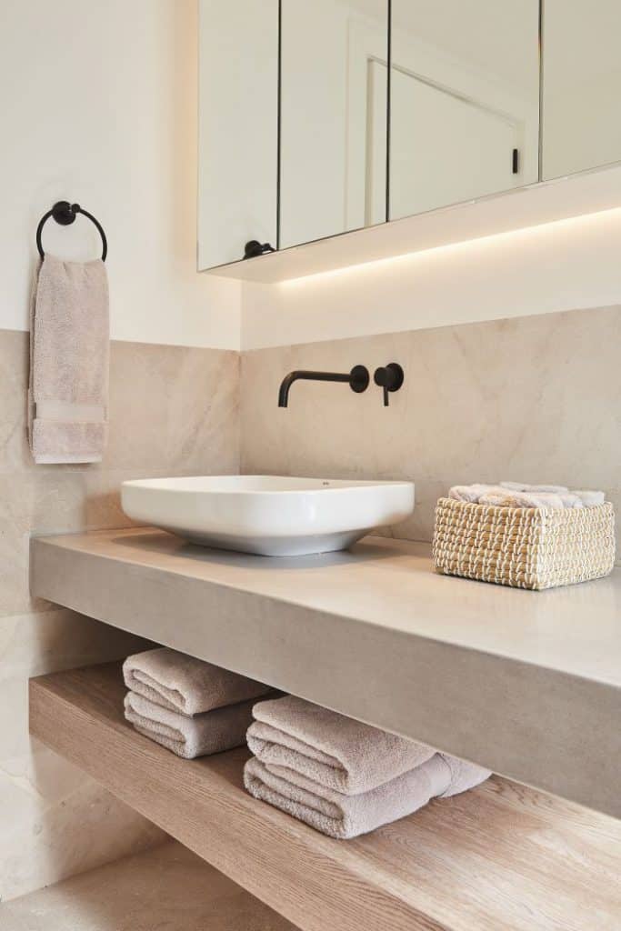 Neutral hardwearing guest bathroom with stone, wood and micro cement.