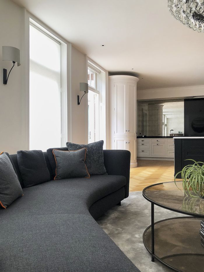 A dark grey minotti curved jacques sofa in an open plan kitchen living room.