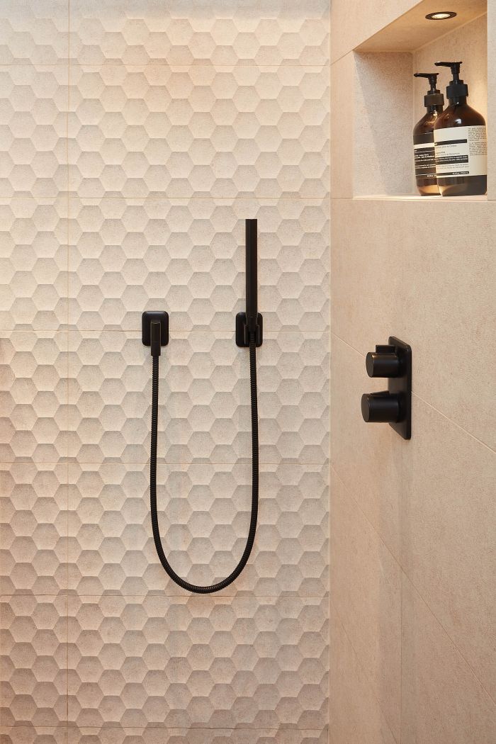 Matt black shower fixtures with beige ceramic Italian tiles. 