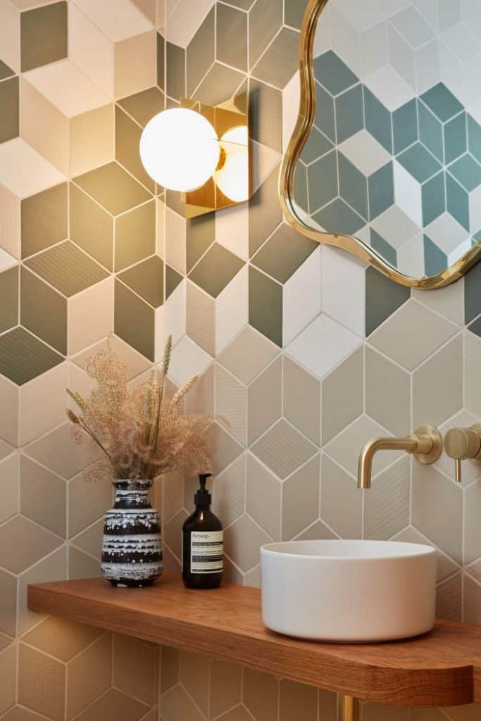 Geometric tile on guest bathroom wall with brass taps.