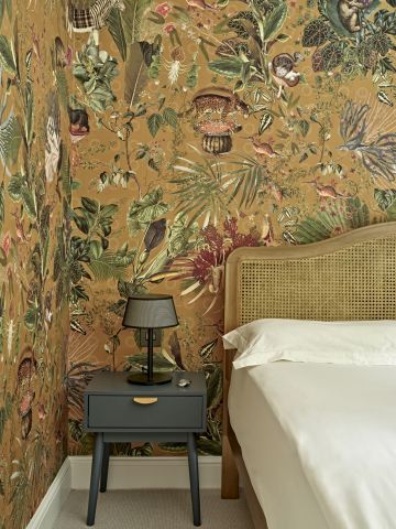 A bold pattern wallpaper with botanicals and animals from Arte International in a bedroom.