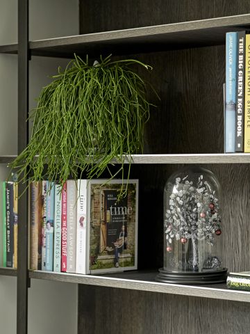 Dark toned wooden book shelf in an open plan kitchen dining room.