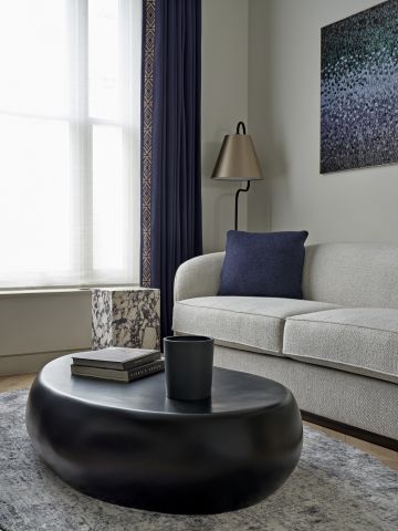 Neutral toned sofa with navy blue cushions decorating it. to harmonise the blue accents there is a blue Aiveen Daly art pice behind the sofa.