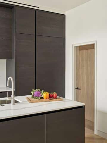 Black ash poliform kitchen with white counter tops.