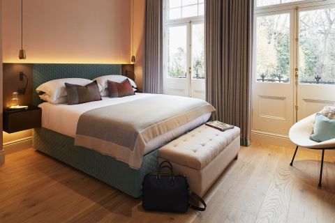 Large principle bedroom with double french door windows and natural wood flooring.