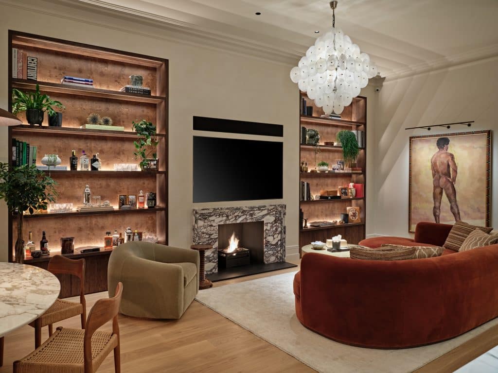 Cozy living space in Central London apartment.On the two sides of the TV and Fireplace there are bespoke shelves displaying sentimental items lovingly collected by the owner.