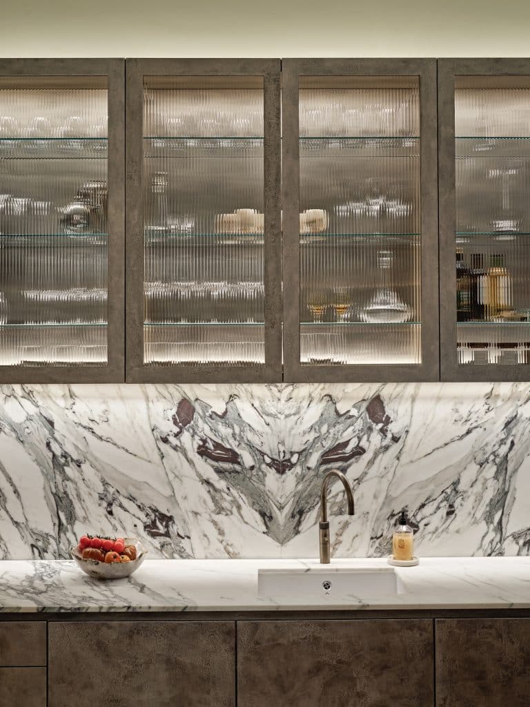 Marble kitchen counter and hand-painted pitted champagne liquid leaf finished cabinets.