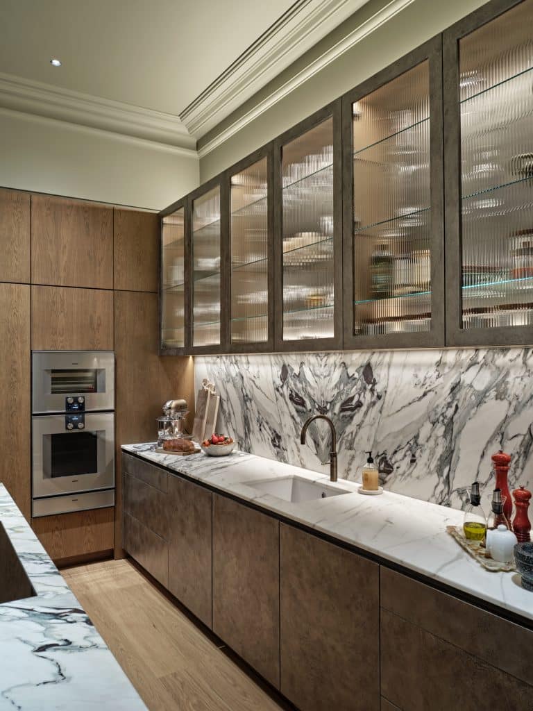 Marble kitchen counter and hand-painted pitted champagne liquid leaf finished cabinets.