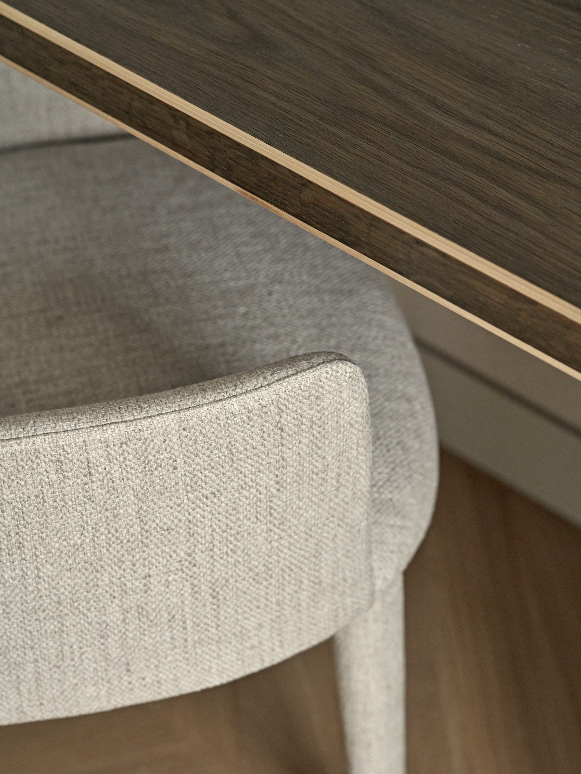 Close up image of a neutral grey toned desk chair from Lema, located in the home study, alongside a dark wood desk.